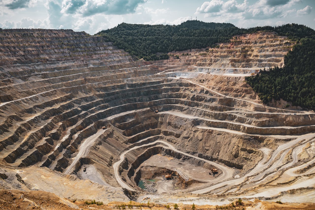 home-hero Aerial view of a large open-pit mine with terraced excavation during summer.